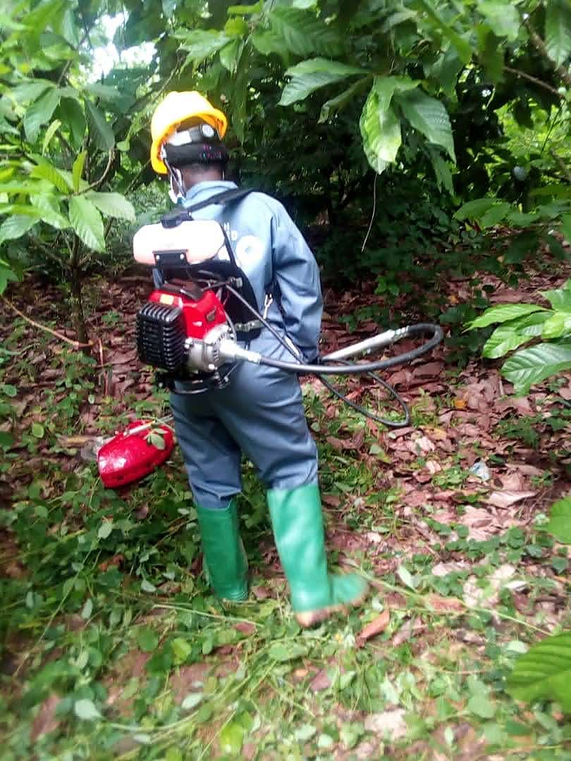 Gadak worker in protective overalls carrying a motorised backpack sprayer